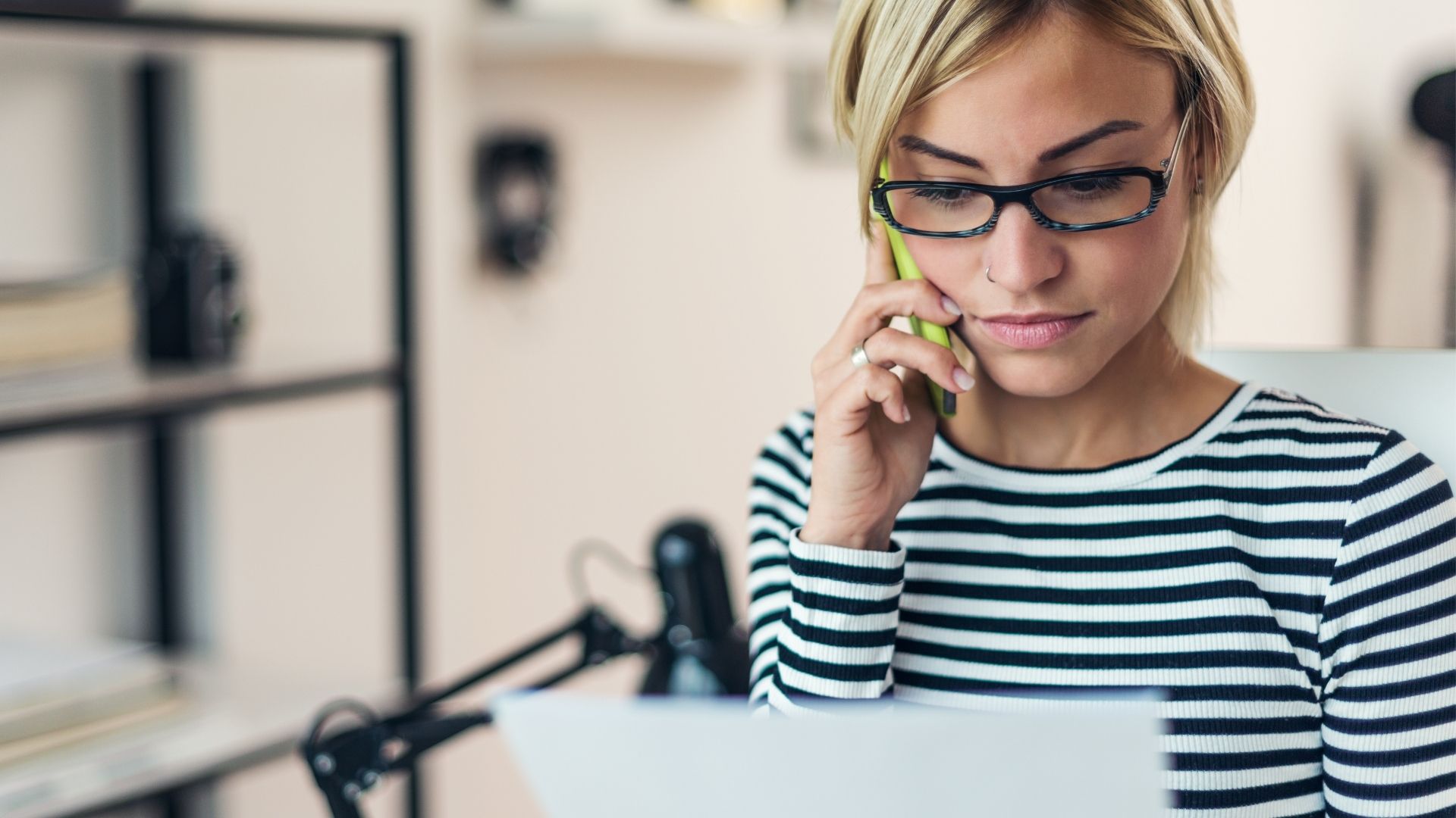 Jeune femme au téléphone lisant un papier qu'elle tient dans la main